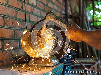 Farmer sharpens a hack on electric grindstone Stock Photo