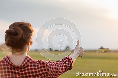 Farmer shows well with a hand to the tractor operator in the field Stock Photo