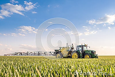 Farmer spraying wheat field with tractor sprayer at spring season Stock Photo
