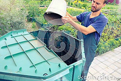 Farmer throws weeds and organic waste from his garden into compost heap. Composting - eco friendly recycling technology. Organic Stock Photo