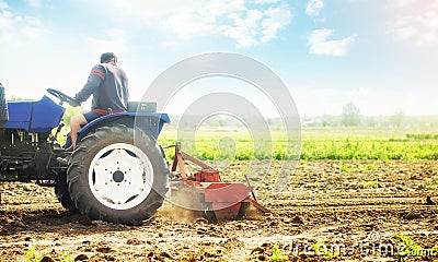 Farmer on a tractor cultivates a farm field. Work on preparing the soil for a new sowing of seeds of agricultural crops. Soil Stock Photo