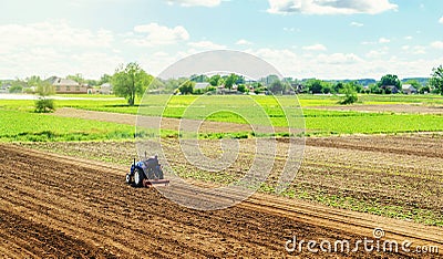Farmer on a tractor with milling machine loosens, grinds and mixes ground. Cultivating land soil for further planting. Loosening, Stock Photo