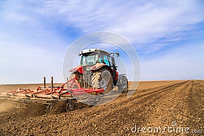 Farmer in tractor preparing land with seedbed cultivator. Stock Photo