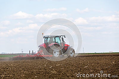 Farmer in tractor preparing land with seedbed cultivator. Stock Photo