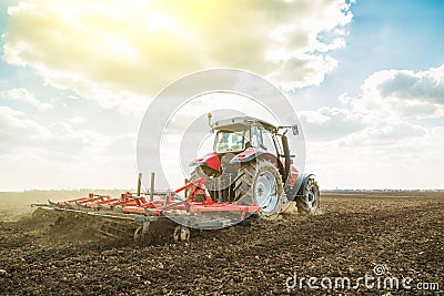 Farmer in tractor preparing land with seedbed cultivator. Stock Photo