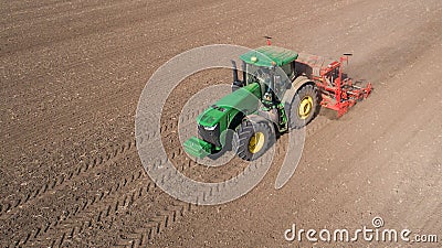 Farmer with tractor with seeder, sowing seeding crops at agricultural field. Aerial view. Editorial Stock Photo