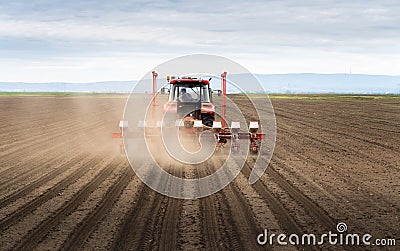 Farmer with tractor seeding crops at field Stock Photo