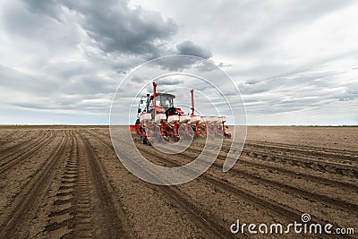 Farmer with tractor seeding crops at field Stock Photo