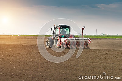 Farmer with tractor seeding - sowing crops at agricultural field Stock Photo