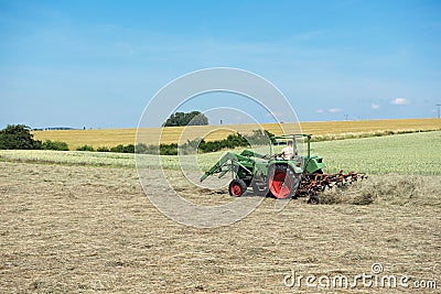 Farmer tractor turns the grass for better drying Editorial Stock Photo