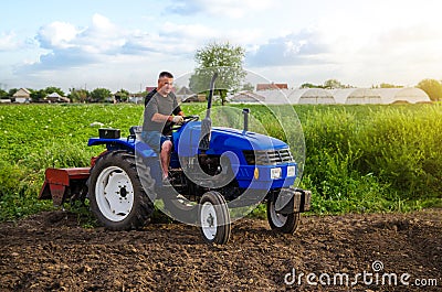 Farmer on a tractor works in the field. Land cultivation. Seasonal worker. Recruiting and hiring employees for work in the farm. Stock Photo
