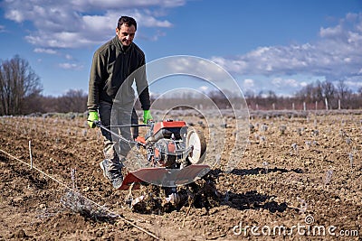 Farmer weeding the field with a tiller Stock Photo