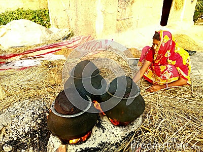 A farmer women with a clay woven processing food grains from paddy by heating. Stock Photo