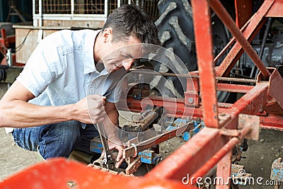 Farmer Working On Agricultural Equipment In Barn Stock Photo