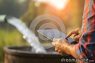 Farmer working in the rice field. Man using digital tablet to control quantity of water to release to his field.Smart farming Stock Photo