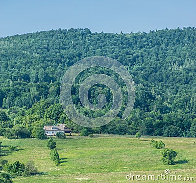 Farmhouse, field and hilly forest Stock Photo