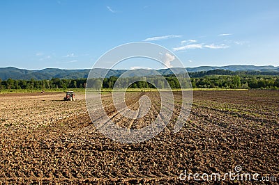 Farming with tractor and plow in field with mountain Papuk in Croatia Stock Photo