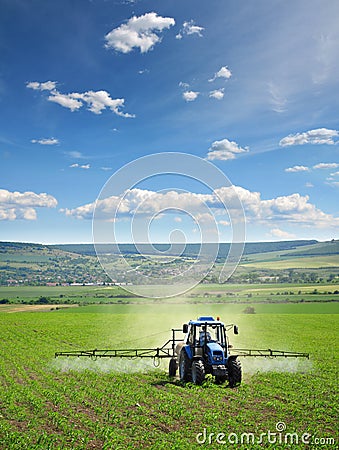 Farming tractor plowing and spraying on field Stock Photo
