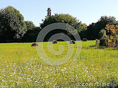 Farmlands in italy with wildflowers haybales and church Stock Photo