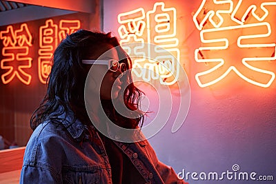 Fashion African girl wears trendy glasses stands near neon sign in night club. Stock Photo