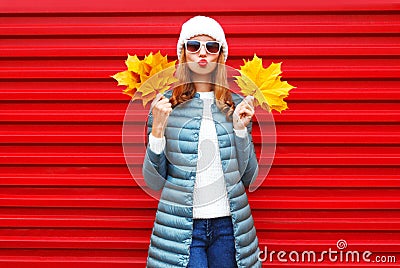 Fashion autumn woman holds yellow maple leaves on a red Stock Photo