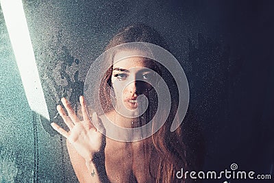 Fashion beauty and love. Rain drops on window glass in heart shape. woman behind plastic sheet with water drops Stock Photo