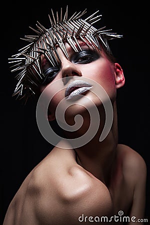 Fashion beauty model with metallic headwear and shiny silver red makeup and blue eyes and red eyebrows on black background Stock Photo