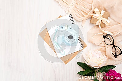 Fashion blogger home office desk with woman items : modern instant photo camera, paper notepad, beige scarf, peonies flowers, Stock Photo