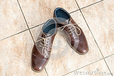 Fashion brown men`s shoes on a light brown ceramic tiles Stock Photo