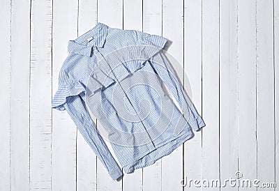 Fashion clothes. Blue and white striped shirt with flounce on white wooden floor planks Stock Photo