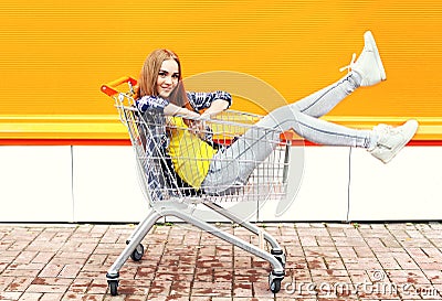 Fashion cool girl having fun sitting in shopping trolley cart Stock Photo