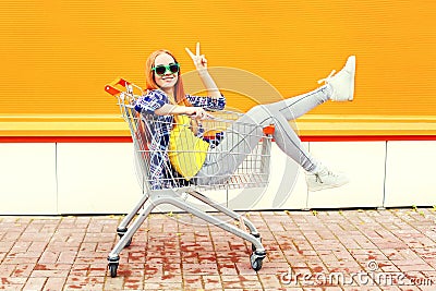 Fashion cool smiling girl having fun sitting in shopping trolley cart Stock Photo