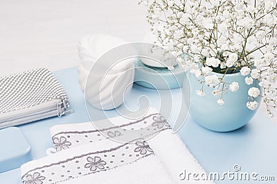 Fashion cosmetic products - white soap, towel, flowers, soap dispenser, blue ceramic vase, silver cosmetic bag on white wood. Stock Photo