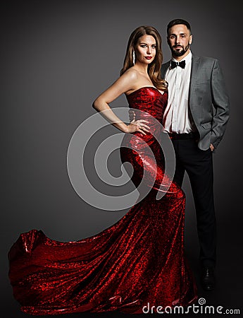 Fashion Couple. Beauty Woman in Red Dress and Handsome Man in Classic Suit with Bow Tie. Elegant Lady in Luxury Gown and Gentlemen Stock Photo