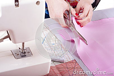 Fashion designer concept. Womans hands cutting pink fabric in studio Stock Photo