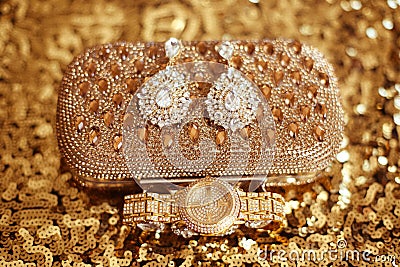 Fashion diamond earrings and golden wristwatch, womens accessories precious Gem Jewel Set on sequins sparkling sequined textile. Stock Photo