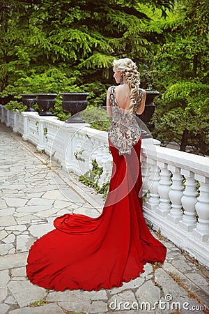Fashion elegant blond woman model in red gown with long train of Stock Photo