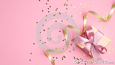 Fashion gift box with pink ribbon bow, golden streamer and confetti star on pink background top view. Flat lay composition for Stock Photo
