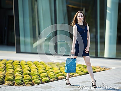 Fashion girl with bag in hand on the street. Happy. Stock Photo