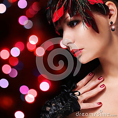 Fashion girl with feathers. Glamour young woman with red lipstick and lace gloves over Bokeh background. Portrait. Evening Makeup Stock Photo