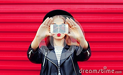 Fashion glamour woman makes self portrait on smartphone blowing lips over city pink Stock Photo