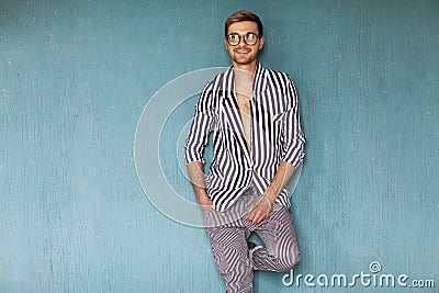 Fashion guy sitting on a blue background in the studio Stock Photo