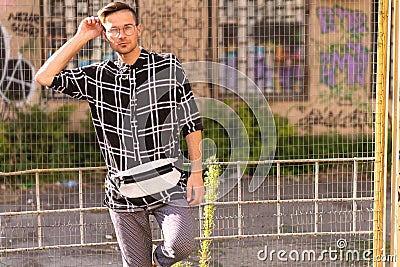 Fashion guy stands posing near the stadium at sunset Stock Photo