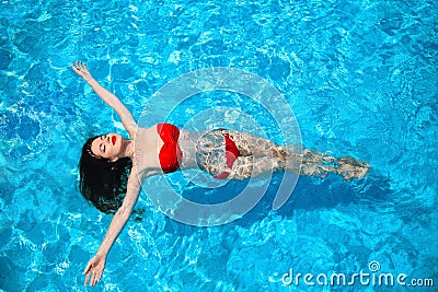 Fashion idyllic bikini tanned woman swimming on surface of Stock Photo