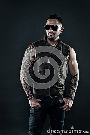 Fashion macho in trendy sunglasses. Tattoo model with beard on unshaven face. Bearded man with tattoo on strong arms Stock Photo