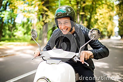 Fashion handsome man driving a scooter in helmet in old town Stock Photo