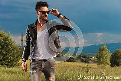 Fashion man in leather jacket putting on his sunglasses Stock Photo