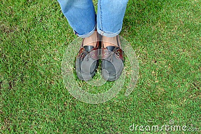 Fashion Man is Legs in Blue Jeans and Wear Vintage Shoes on Green Grass Background Stock Photo