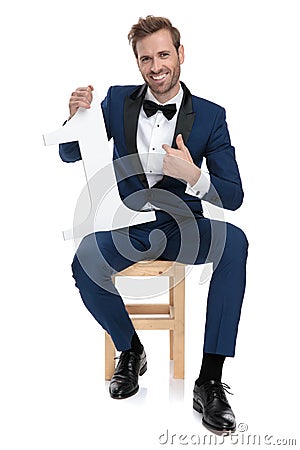 Fashion man wearing groom suit holding a number one sign Stock Photo