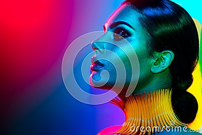 Fashion model woman in colorful bright lights posing. Portrait of girl with trendy makeup Stock Photo